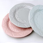 Trzy talerze ceramiczne w pastelowych kolorach z geometrycznym wzorem na krawędziach, idealne do dekoracji wnętrz i serwowania potraw w domu.