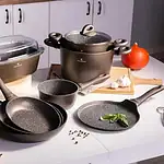 Wysokiej jakości zestaw naczyń kuchennych Valdinox na indukcję, w tym patelnie, garnki i forma do zapiekania, idealny do domowego gotowania i pieczenia, ergonomiczne uchwyty, czarno-szara kolorystyka, nowoczesny design, praktyczne akcesoria w tle, sezonowe składniki.
