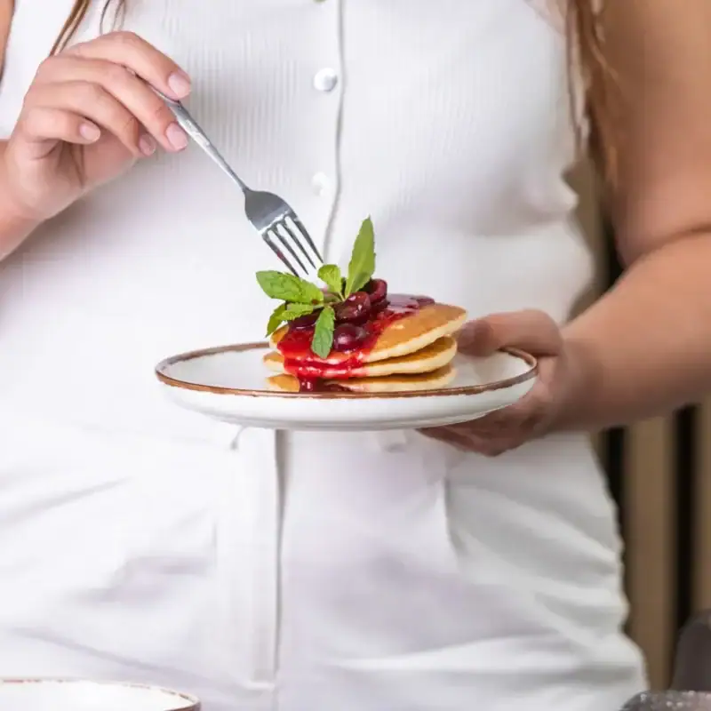 Pierwszy plan na danie z naleśników z owocami i miętą, elegancko podany na białym talerzu. Idealny deser lub śniadanie, atrakcyjny wizualnie i smakowo, wpisujący się w trend zdrowych i estetycznych posiłków.
