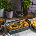 świeże zioła w doniczkach na stole, domowy ogródek z bazylią, miętą i tymiankiem, dekoracyjne naczynia ceramiczne, naturalny klimat, zdrowa kuchnia, inspiracje do domowego gotowania, kulinarne akcesoria, domowe smaki, rustykalny wystrój kuchni.